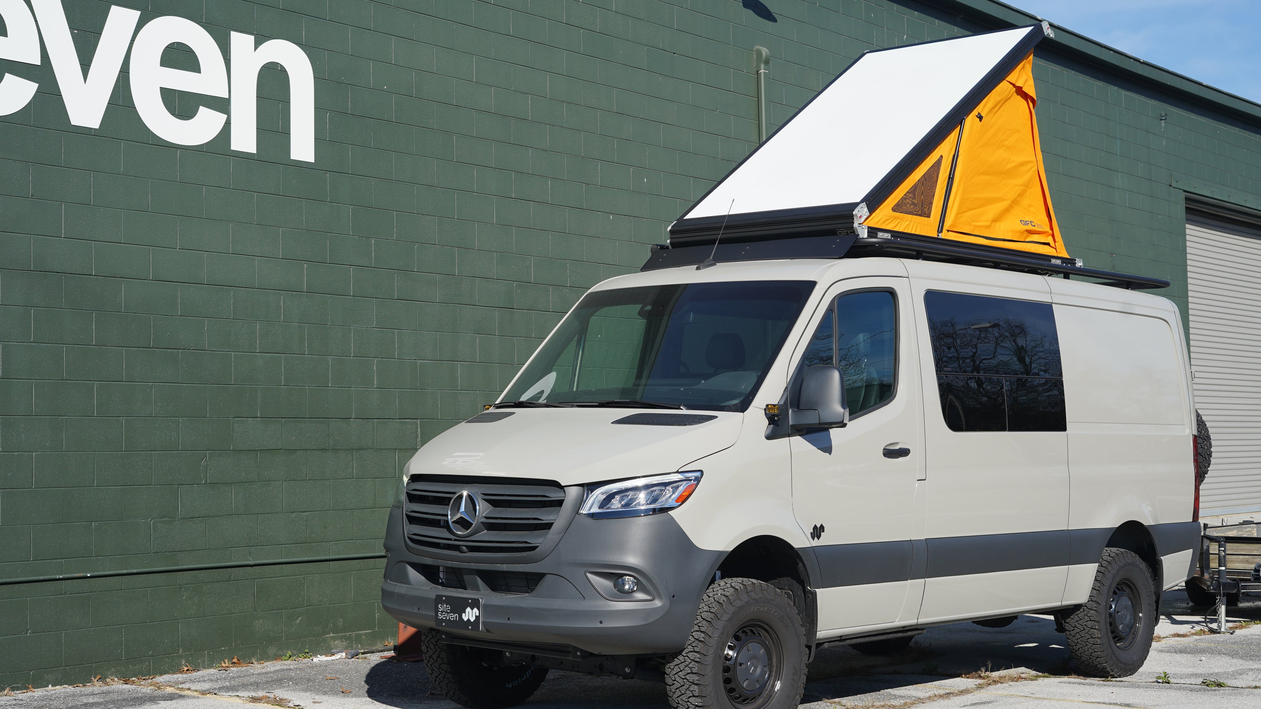 Van with a rooftop tent parked in front of a building 