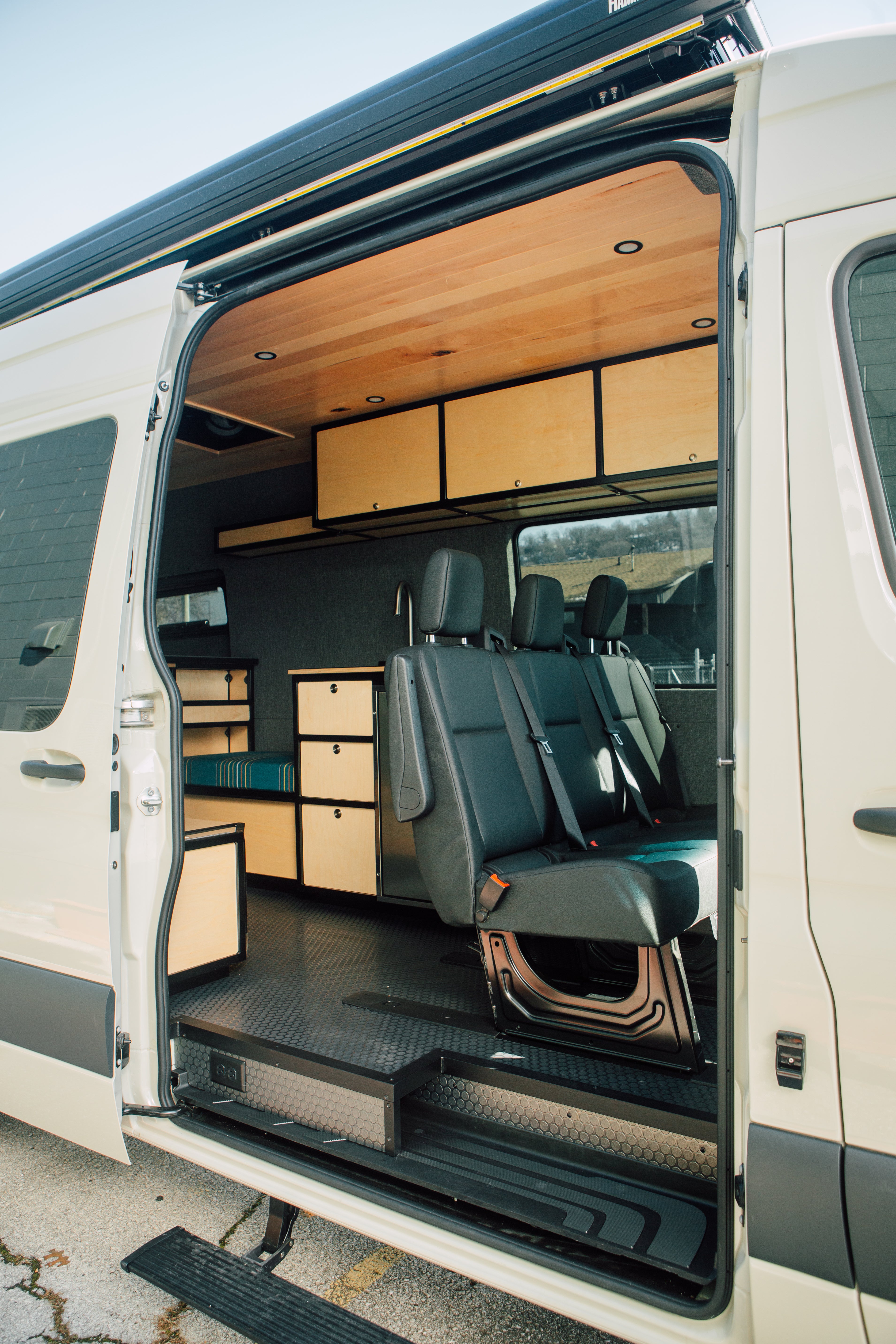 Van interior with open doors showing seating and storage compartments.